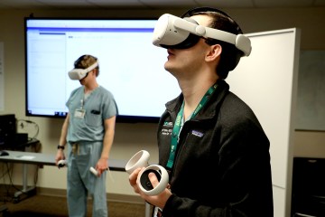Two men in medical scrubs wearing virtual reality headsets