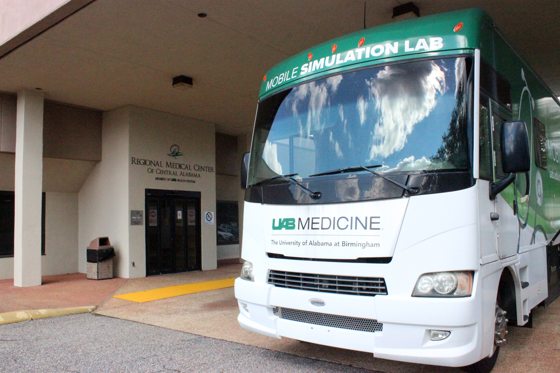 A white and green bus sitting outside of a hospital.