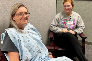 Two women seated in a room, one wearing a medical gown as part of a simulation