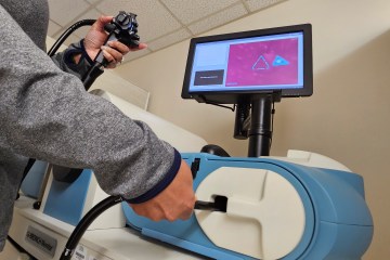 A person's hands controlling a probe on a health-care simulation trainer