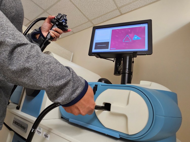 A person's hands controlling a probe on a health-care simulation trainer