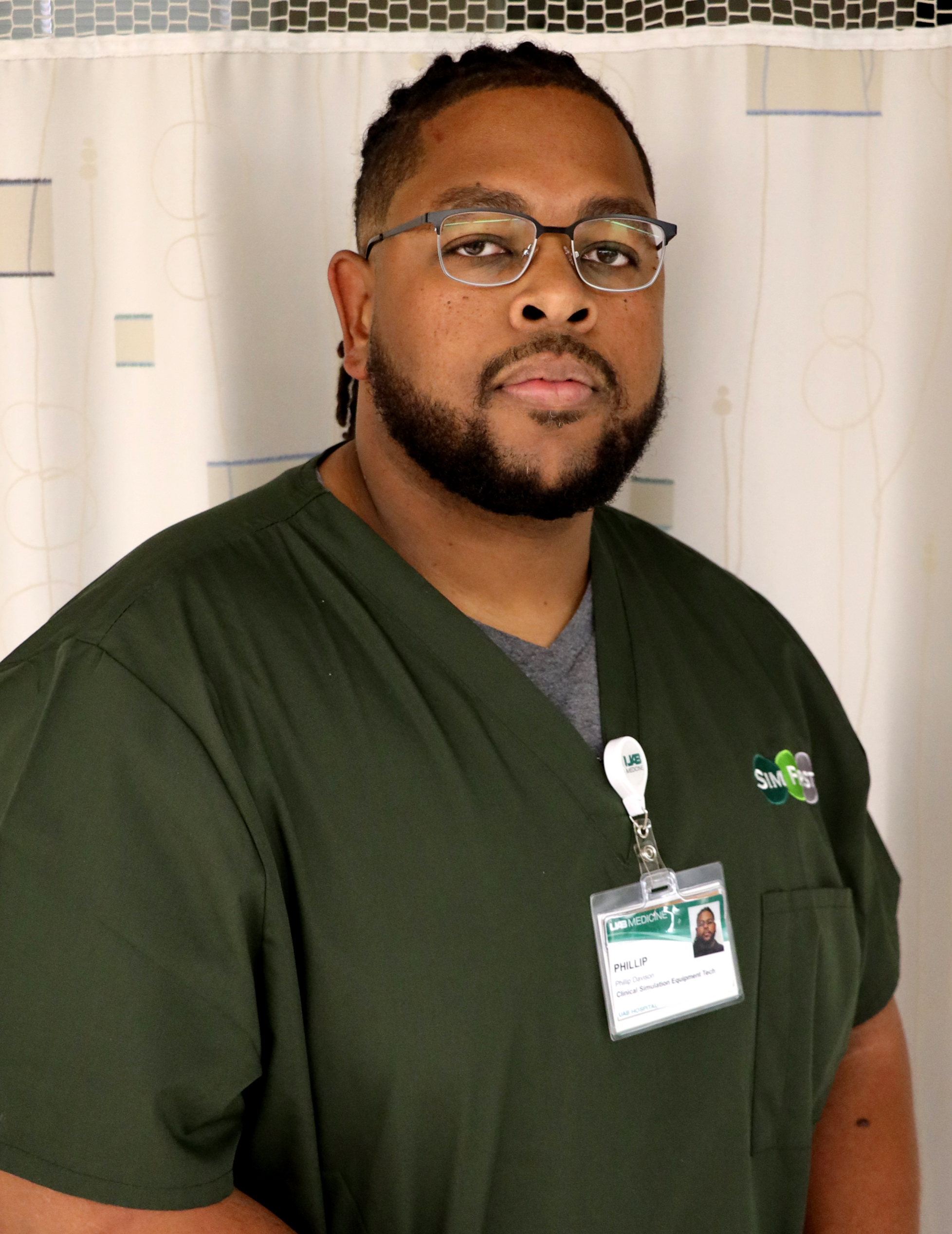 A Black man in olive green medical scrubs