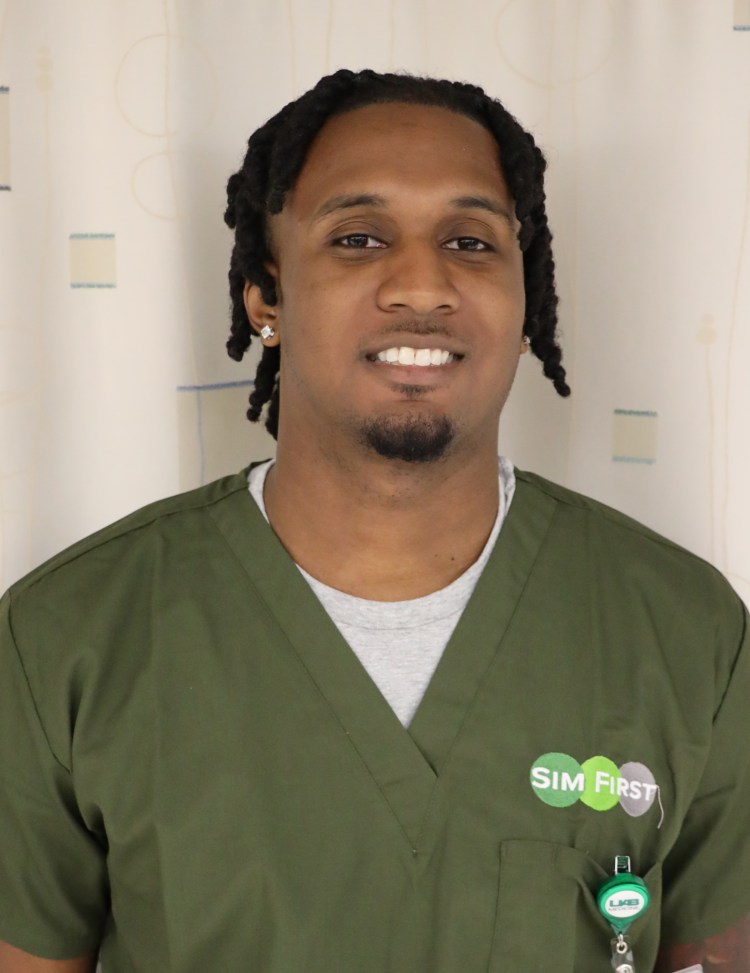 A Black man in olive green medical scrubs