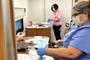 Two Caucasian women, one blue medical scrubs and the other in a pink tie-dyed shirt and black scrub pants, participating in a health-care simulation in a mobile simulation lab