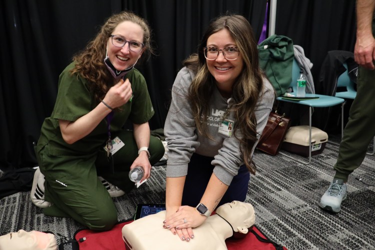 Two Caucasian women smiling for a photo while demonstrating CRP on a health-care simulation manikin