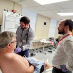 Two physicians examining a standardized patient as part of an ultrasound health-care simulation