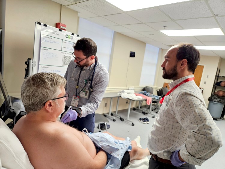 Two physicians examining a standardized patient as part of an ultrasound health-care simulation