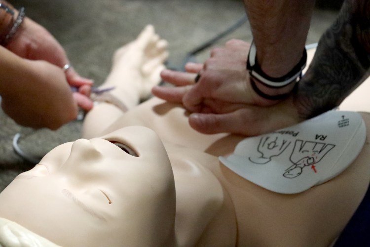 A close-up of two nurses' hands simulating code skills response on a simulation manikin