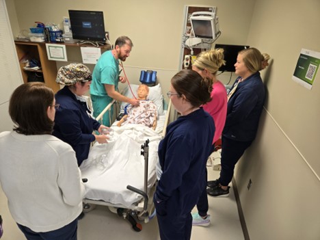 A group of medical professionals participating in a pediatric health-care simulation with a pediatric health-care simulation manikin