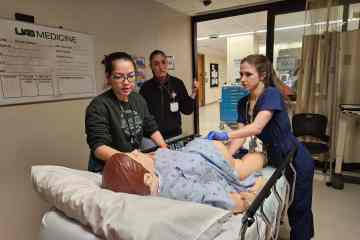 Three female OB/GYN residents participating in a health-care simulation with a health-care manikin