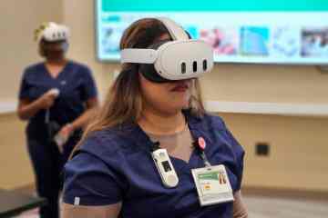 Two women in navy blue medical scrubs wearing white virtual reality headsets