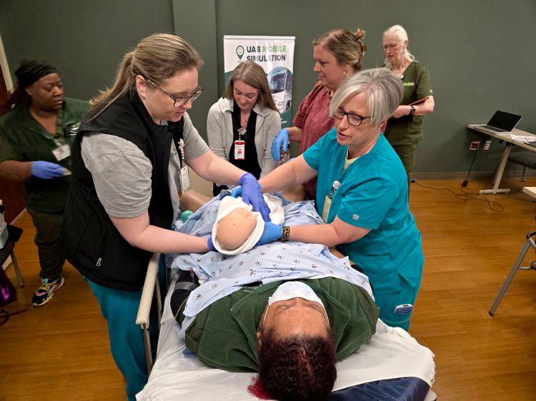 Four nurses participating in a obstetric health-care simulation featuring a standardized patient, as simulation facilitators observe and assist