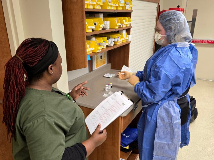 A health-care simulationist guiding a learner through a sterile compounding simulation