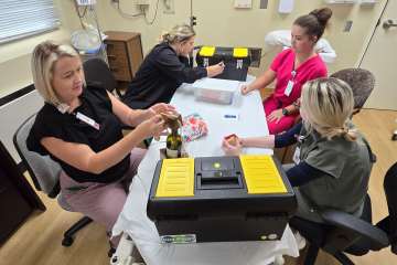 Four nurses sitting at a table participating in a tabletop health-care simulation