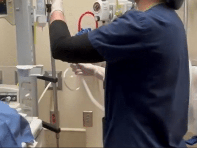 A nurse in navy blue scrubs preparing a chest tube
