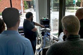 A group of male individuals studying a lung simulator as part of a pilot simulation