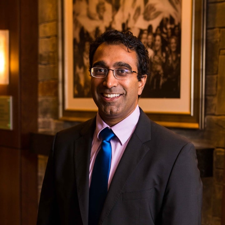 A man in a dark gray suit with blue necktie