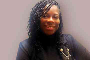 A smiling woman with black hair wearing a black blazer and black top
