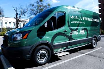 A green Ford Transit van marked as the UAB Mobile Simulation Lab