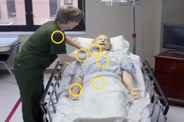 A woman in olive green medical scrubs interacting with a health-care manikin as part of a virtual health-care simulation