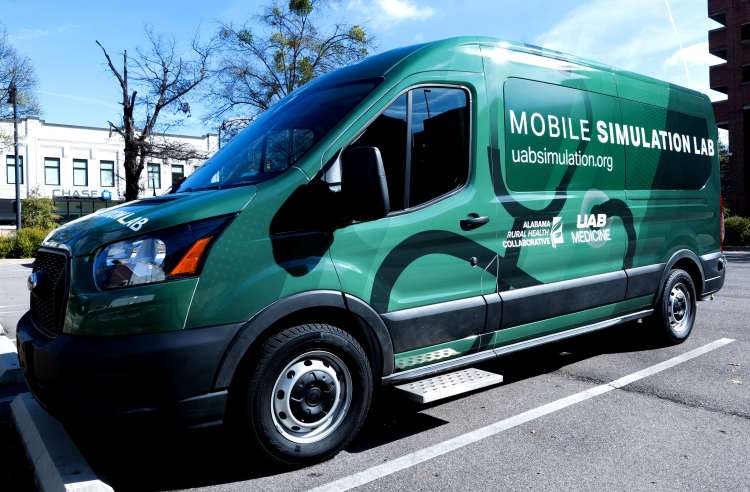 A dark green utility van with "Mobile Simulation Lab," "Alabama Rural Health Collaborative" and "UAB Medicine" written in white on the side.
