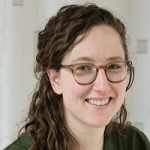 A Caucasian woman wearing olive green medical scrubs