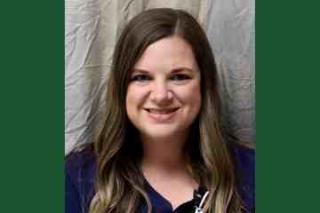 A headshot of woman in navy blue medical scrubs