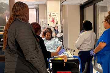 An interprofessional group of healthcare professionals surrounding a standardized patient dressed in a hospital gown portraying a disruptive patient