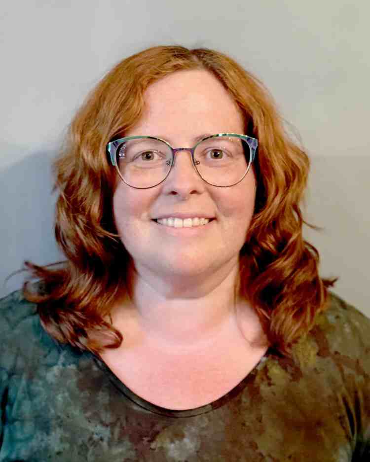 A woman with red hair, glasses and a dark blouse