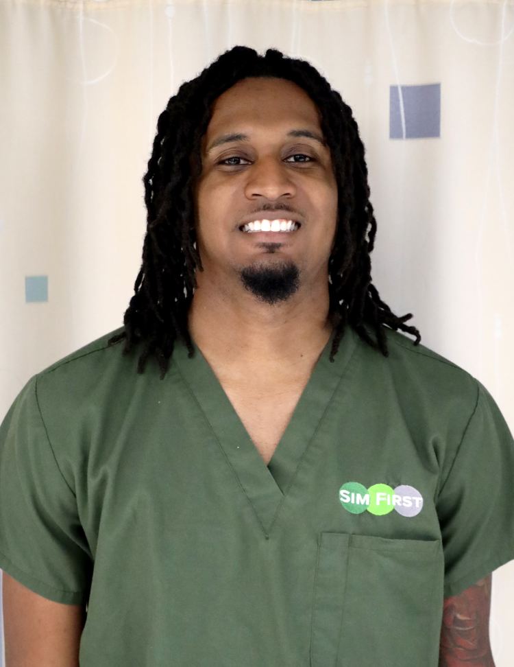 A young man in olive green medical scrubs