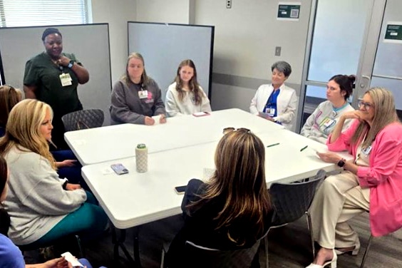 A group of female healthcare professionals seated around two tables while discussing a healthcare simulation experience