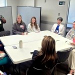 A group of female healthcare professionals seated around two tables while discussing a healthcare simulation experience