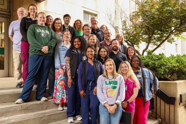 A diverse group of interprofessional healthcare team members standing on an outdoor staircase for a photo