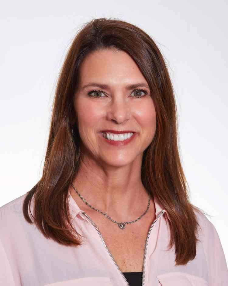 A headshot of a Caucasian woman with brown hair wearing a white blouse